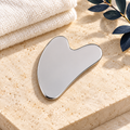 Noble Stainless Gua Sha on cream stone